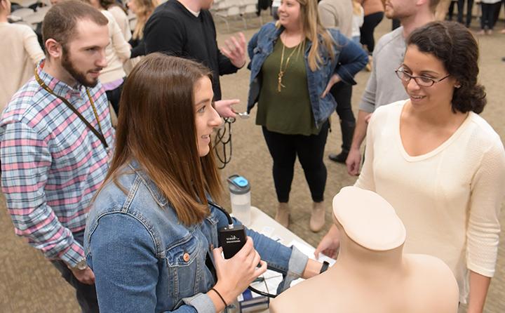 Students practicing medical techniques on a mannequin 